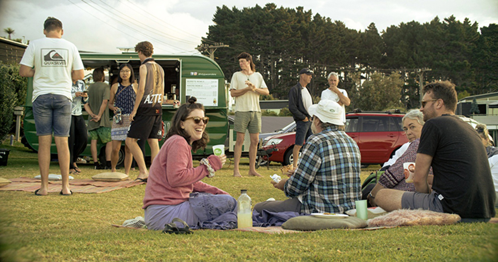 People sitting near a food truck eating